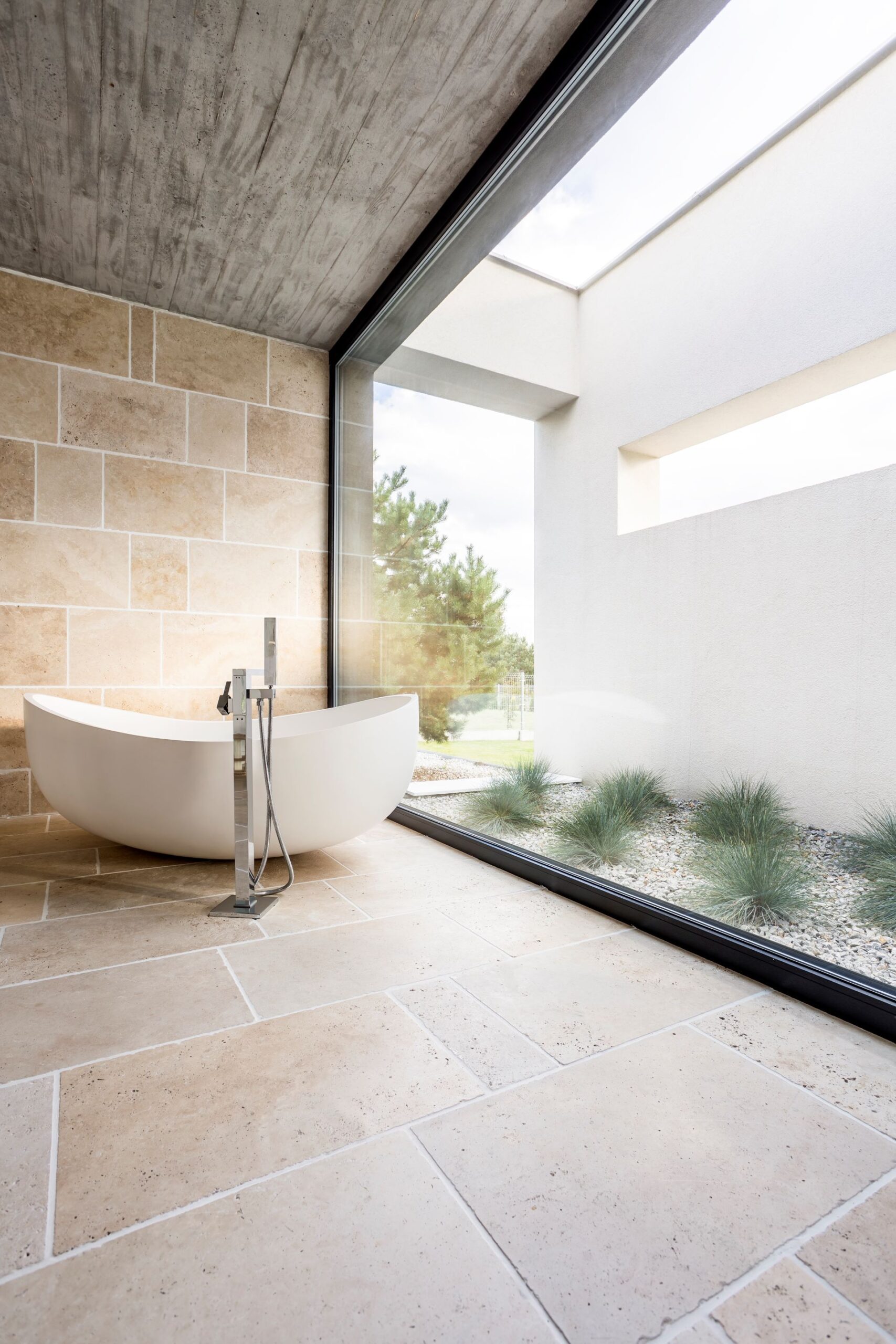 Modern bathroom with freestanding tub and garden view.