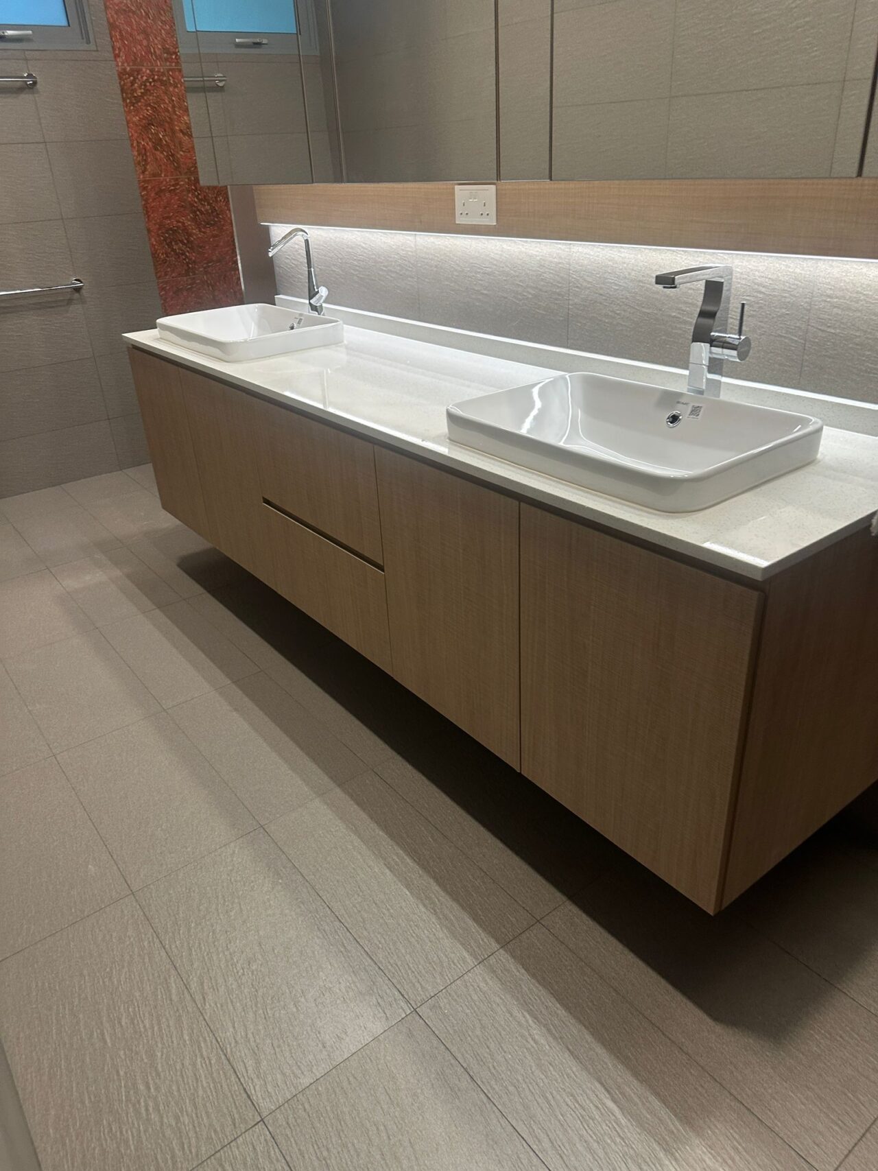 Modern bathroom with double sinks and wooden cabinet.